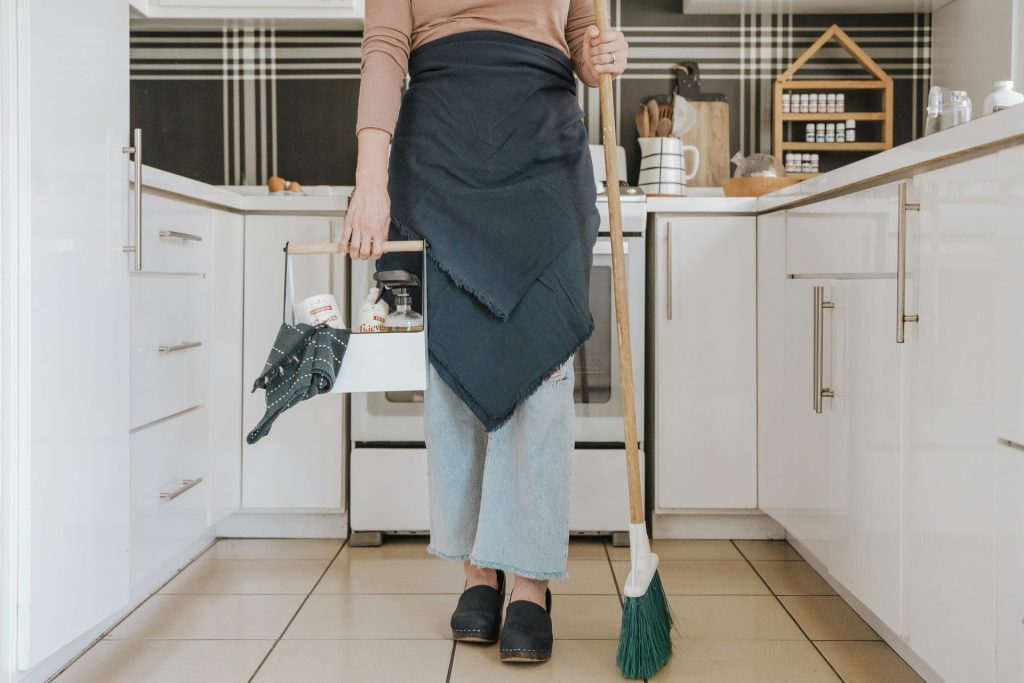 eine Frau, die in einer Küche steht und einen Besen hält